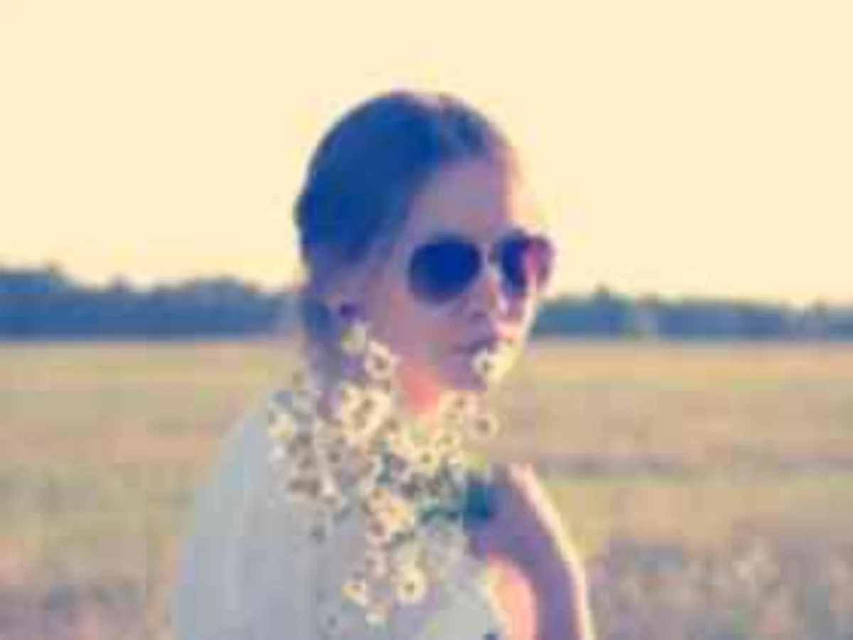 Low-resolution photo of a woman in sunglasses in a field, before enhancement